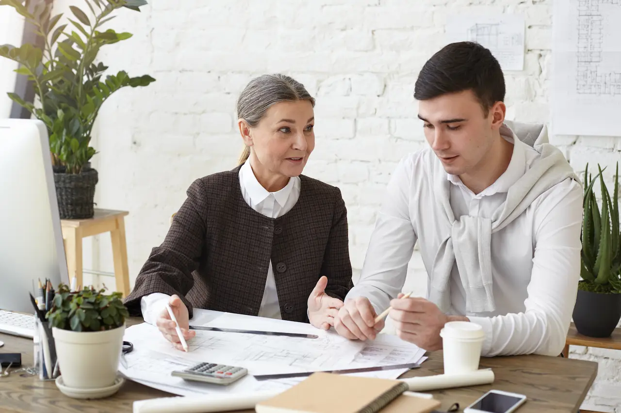 Architect and client reviewing house plans and discussing construction project at office desk