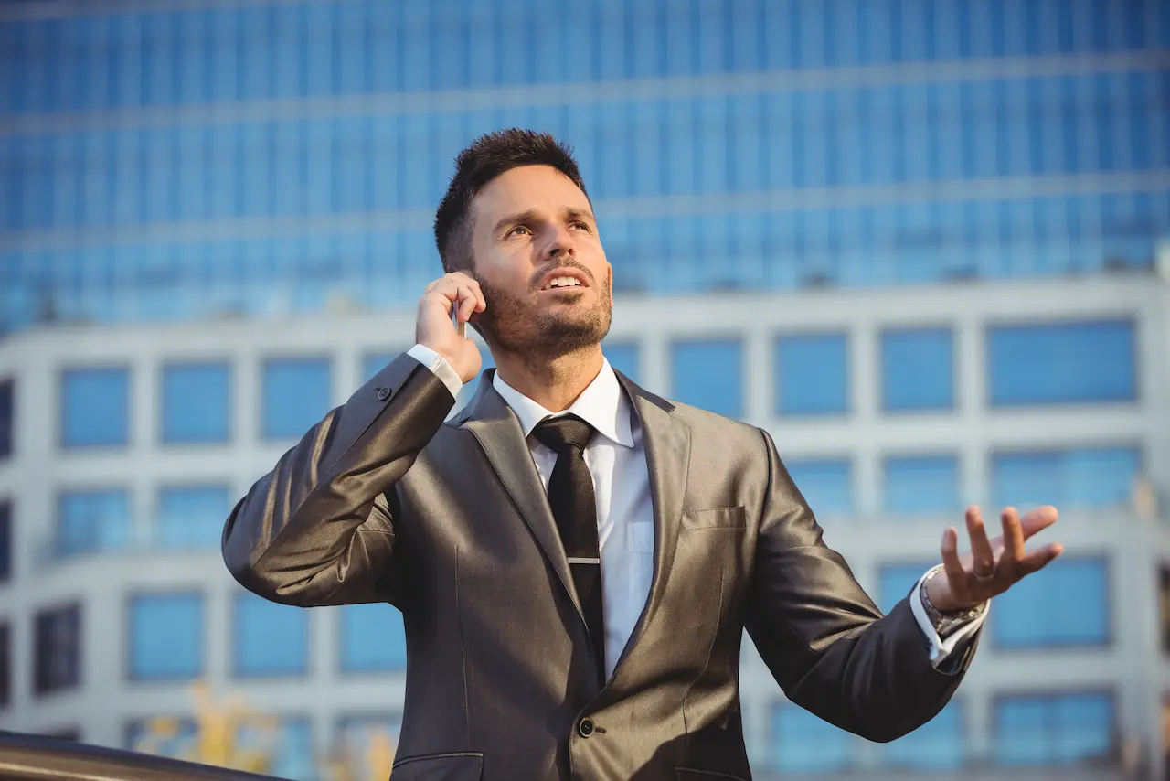 Businessman in suit talking on mobile phone outside a modern office building