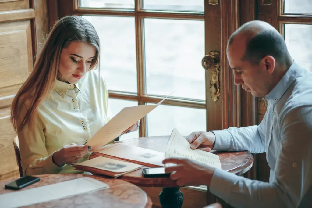 Man and woman sitting at a table reading documents together in a cafe